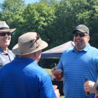 4 men talk by golf carts